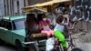 Usando máscara de protección contra el coronavirus, un hombre trasporta a clientes en un bicitaxi en La Habana. (AP/Ramon Espinosa)