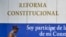 Una cubana camina frente a un poster donde se anuncia la reforma Constitucional.
