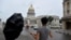 Un turista chino ajusta su paraguas en medio de una tormenta frente al capitolio de La Habana. (REUTERS/Norlys Perez/Archivo)