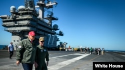 El presidente Donald Trump junto al portaaviones Harry S. Truman.